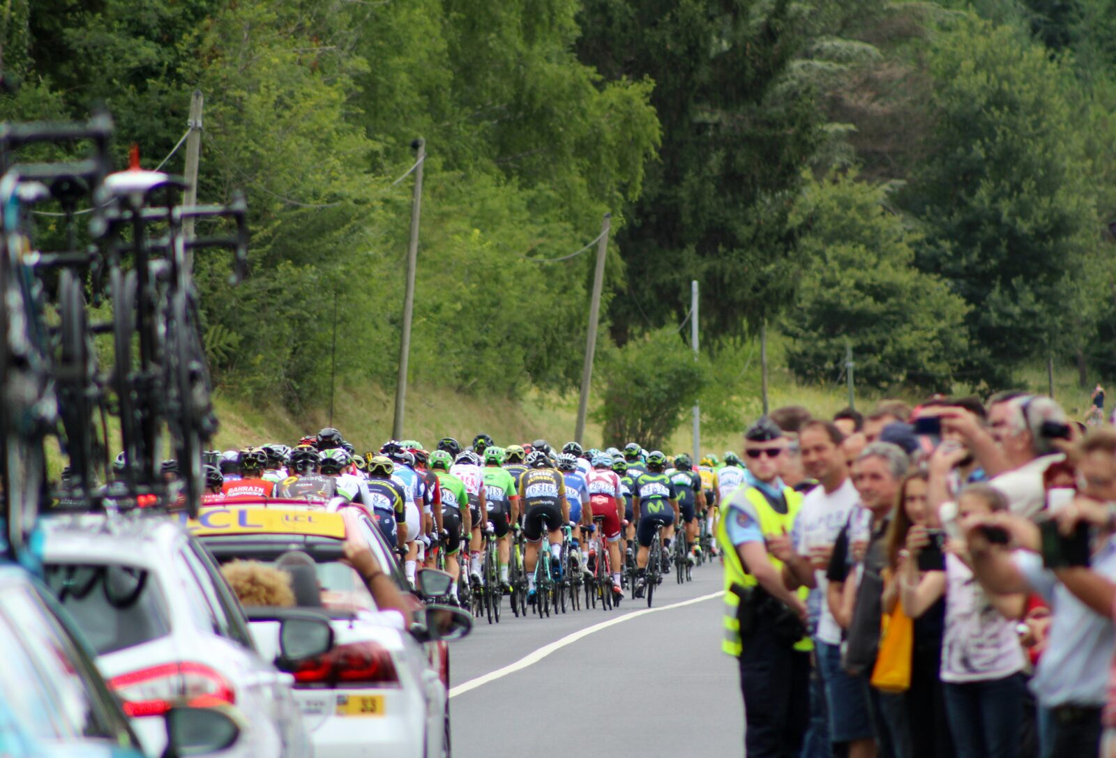 The peloton on an empty rural French road lined with spectators